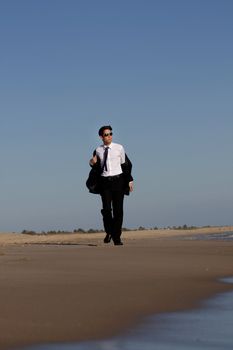 Close up view of a bunisess man in a dark suit walking on the beach.