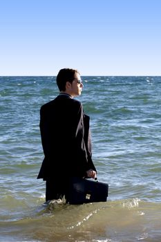 Brave business man in the shoreline of the beach.