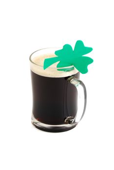 Glass of dark beer decorated with 4-leaf clover on white background