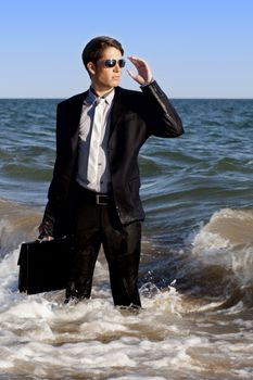 Brave business man in the shoreline of the beach.