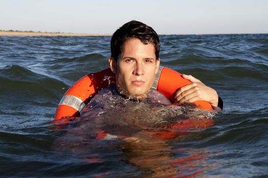 Business man holds a lifesaver buoy on the water.