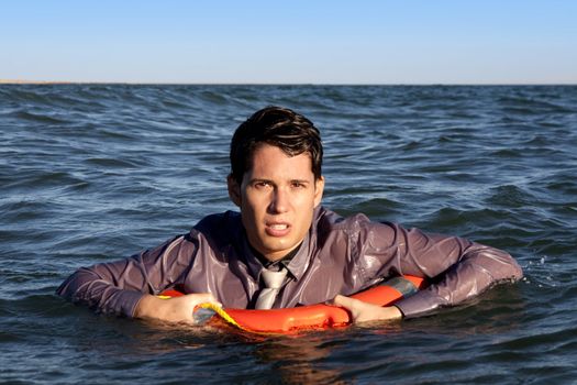 Business man holds a lifesaver buoy on the water.
