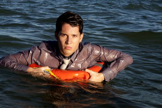 Business man holds a lifesaver buoy on the water.