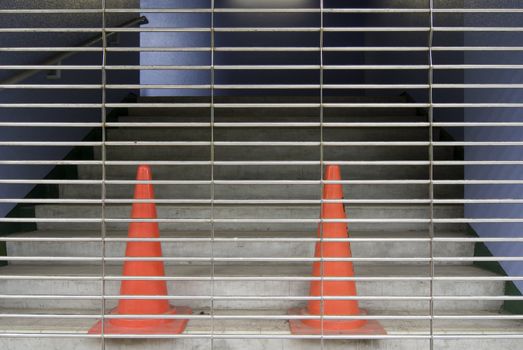 entrance stairs closed with metallic rolls and two red plastic cones