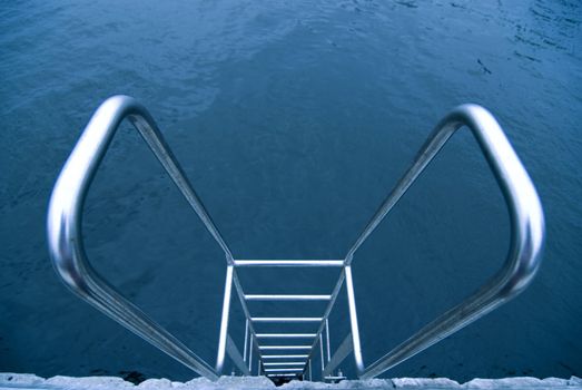 metallic stairs with hand-rails on the swimming pool water background