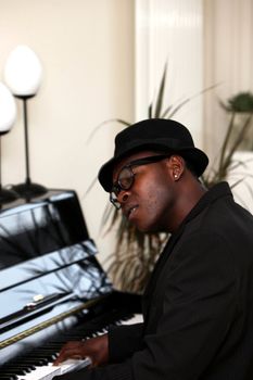 a man - Afro-Africans with hat sitting at the piano and plays
