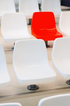 All the chairs are white, one is red - conceptual - vertical image