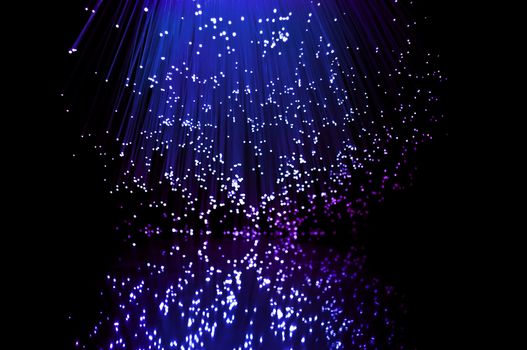 Blue and violet fibre optic light strands reflecting in the foreground.
