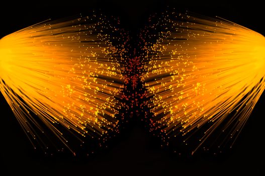 Two illuminated groups of vibrant gold fibre optic strands emanating from the left and right of the image. Black background.