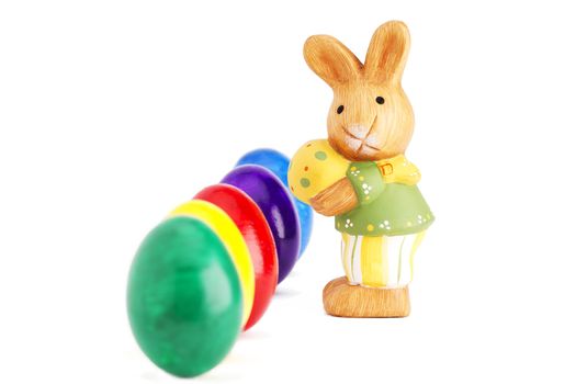 easter bunny figurine in front of deep row of easter eggs on white background