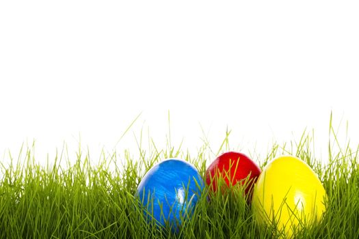 red blue and yellow easter egg in grass with white background