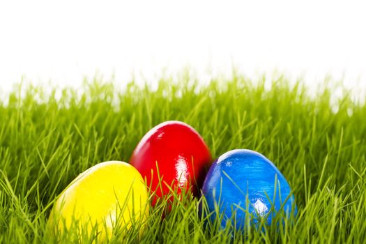 three easter eggs with soft focus in grass on white background