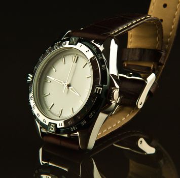 Men watch with a brown leather wristlet on a dark glass table