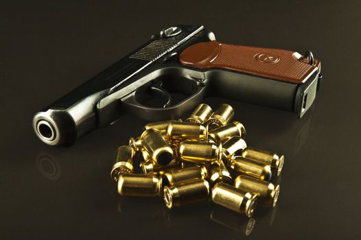 A gun and lots of bullets on a glass table over a dark background