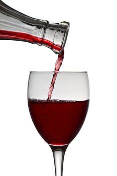 red wine pouring down from a wine decanter into a wine glass on white background