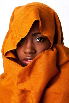 Beautiful mysterious african nomadic female face in ocher Earth tone head wrap scarf looking.