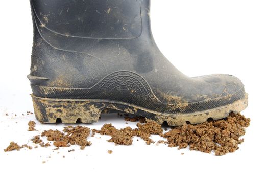 one muddy farmer boot and soil isolated on a white background