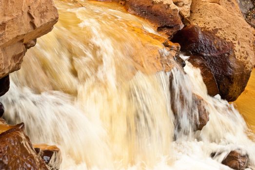 River runs yellow with sediment from gold mining in Colorado mountains near Ouray