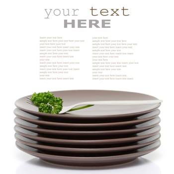 Stack of brown round plates with fork and parsley (with sample text)

