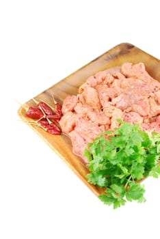 raw pork meat with red pepper and parsley ready to be cooked on a wooden tray (over white)
