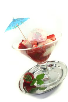 Strawberry ice cream on a silver tray and a fresh strawberry