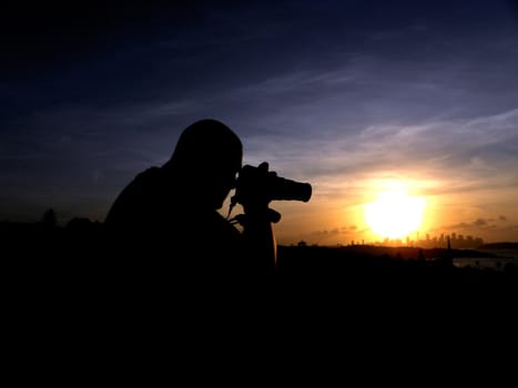 A person who takes a picture at sunset background.