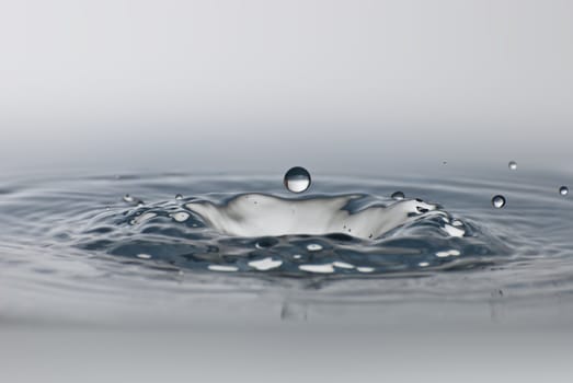 Clean drop of water splashing in clear water. Abstract environmental background.