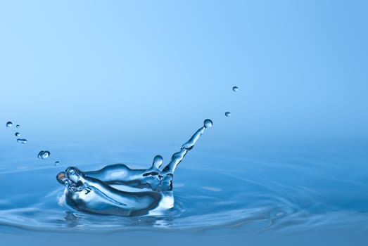 Clean blue drop of water splashing in clear water. Abstract blue environmental background.