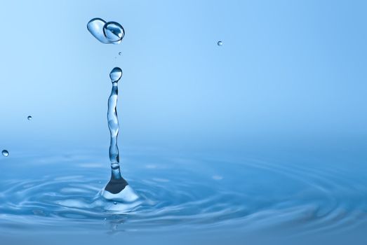 Clean blue drop of water splashing in clear water. Abstract blue environmental background.