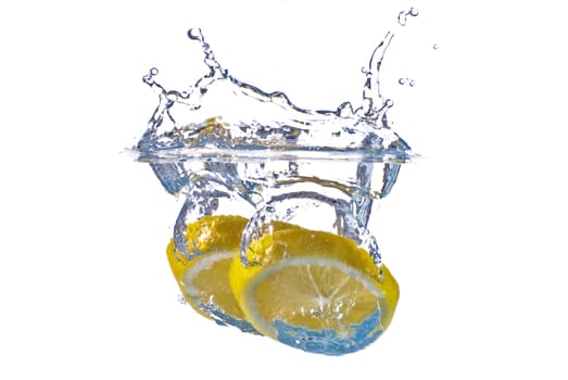 Closeup abstract yellow lemon splashing in clear blue water - isolated against white background.