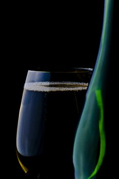 Merry Christmas and happy New year. Champagne glass and bottle isolated on black background.