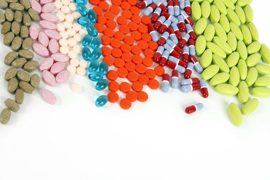 Many different pills lined up on a white background.