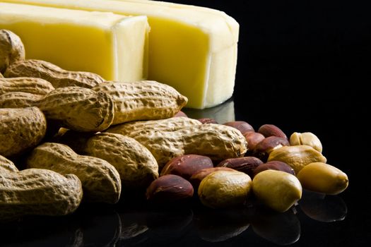 Closeup of peanuts in and out of shell with bars of butter on black background