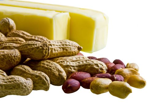 Closeup of peanuts in and out of shell with bars of butter on white background