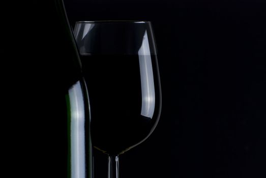 Bottle and glass of red wine isolated on black background
