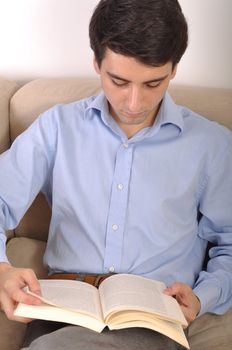 attractive young man reading a business book on the couch