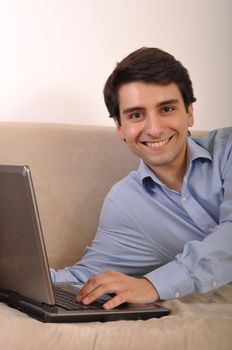 attractive young man with laptop computer lying on the couch at home