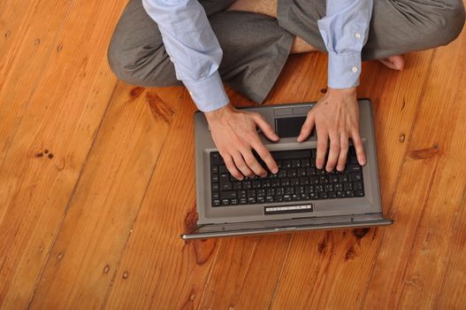 man with laptop computer sitting on the floor at home