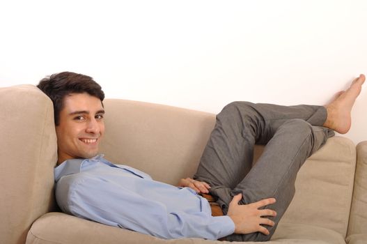 attractive young man lying and relaxing on the couch (isolated on white background)