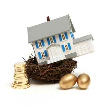 A model house rests in a nest with gold coins and eggs for many investment concepts.