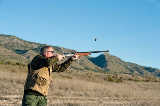 Hunter in action aiming and shooting his rifle