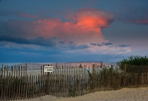 An evening scene at the beach. The last rays of light are dramatically lighting the clouds in the sky of a nearby thunderstorm.