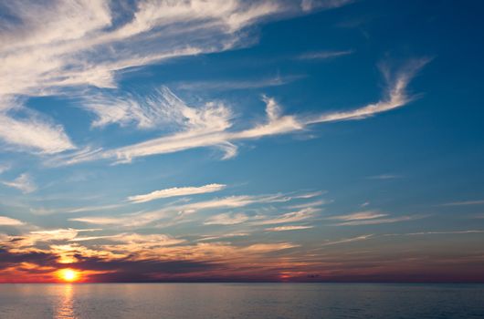 An Evening Sunset Over Water. The sky is blue at the top with multi colors closer to the water.