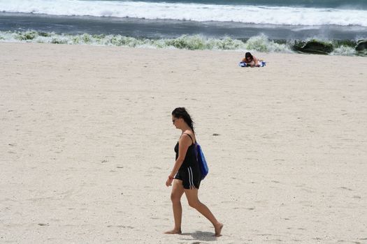 The young woman walking along the beach on a sunny day