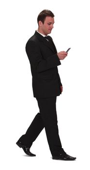 Image of a young businessman walking and checking his mobile phone,isolated against a white background.