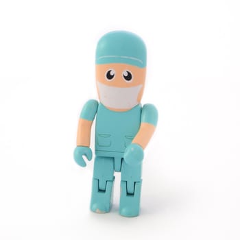 Plastic toy puppet of a surgeon figure wearing green surgery scrubs, isolated on a white background.
