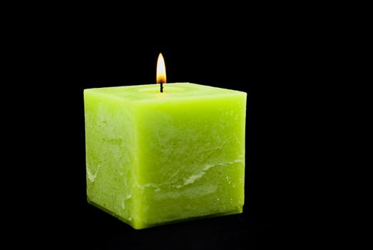 a green candle on a black background.