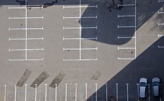 Empty parking with two cars. Picture taken from a height, frontal.