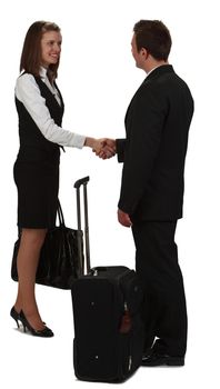 Image of a young businesswoman and a young businessman shaking hands near a roller suitcase, isolated against a white background.