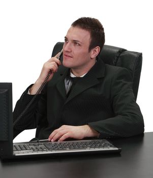 Image of a businessman using a telephone while sitting to his work desk, isolated against a white background.